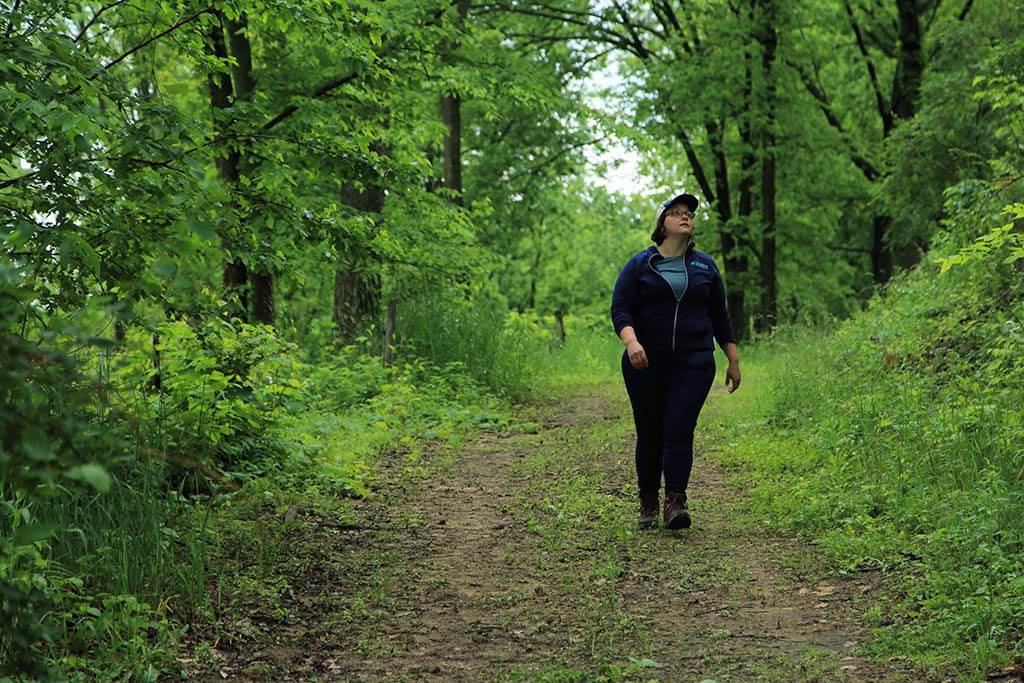 Devon Brock-Montgomery (water quality program manager) walks along wooded road at Savanna Institute's Hillside Farm, Spring Green, Wisconsin.