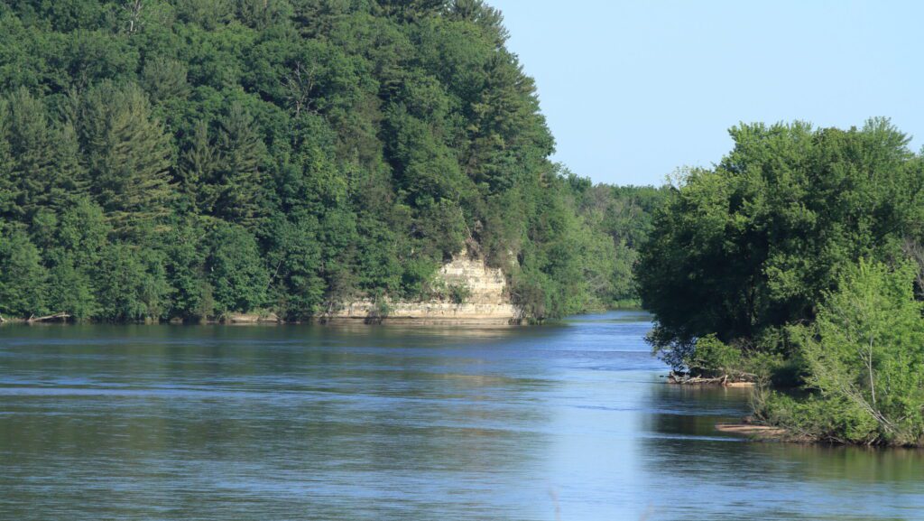 A wide river with trees and cliffs.