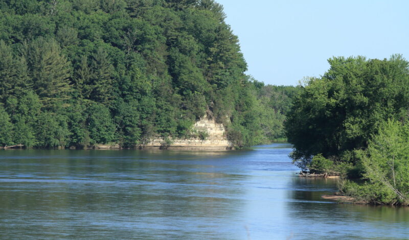 A wide river with trees and cliffs.