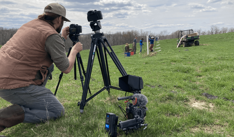 Cameraman filming farm workers.