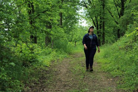 Devon Brock-Montgomery (water quality program manager) walks along wooded road at Savanna Institute's Hillside Farm, Spring Green, Wisconsin.